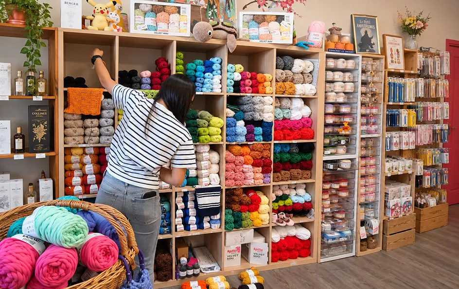 Femme choisissant des laines colorées dans boutique artisanale créative et gourmande