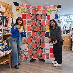 Deux personnes posant devant un patchwork coloré dans une boutique artisanale et créative