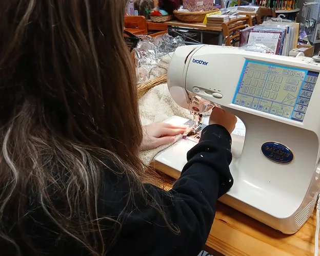 Femme utilisant une machine à coudre Brother dans un atelier créatif.