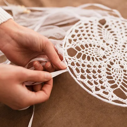 Mains travaillant une dentelle blanche.