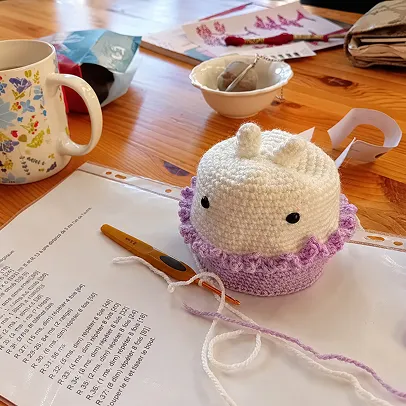 Petit personnage réalisé au crochet avec de la laine blanche et violette.