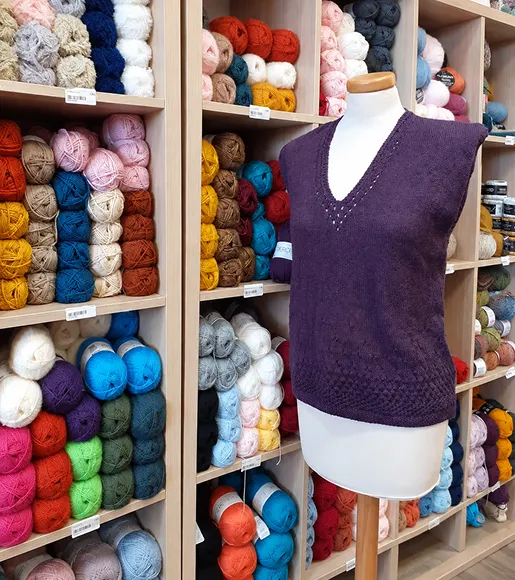 Mannequin présentant un pull en laine mauve dans boutique spécialisée.