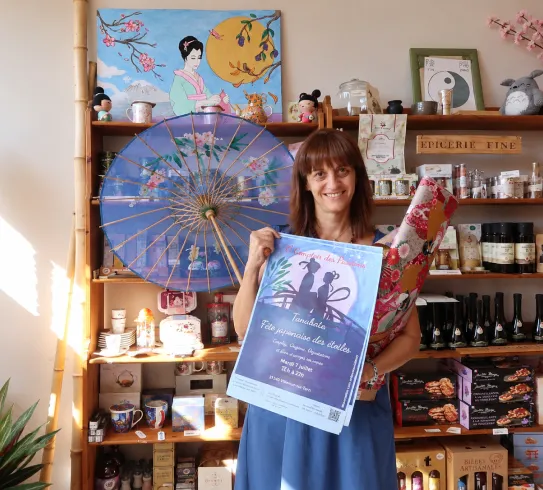 Femme tenant une affiche événementielle dans boutique artisanale et épicerie fine